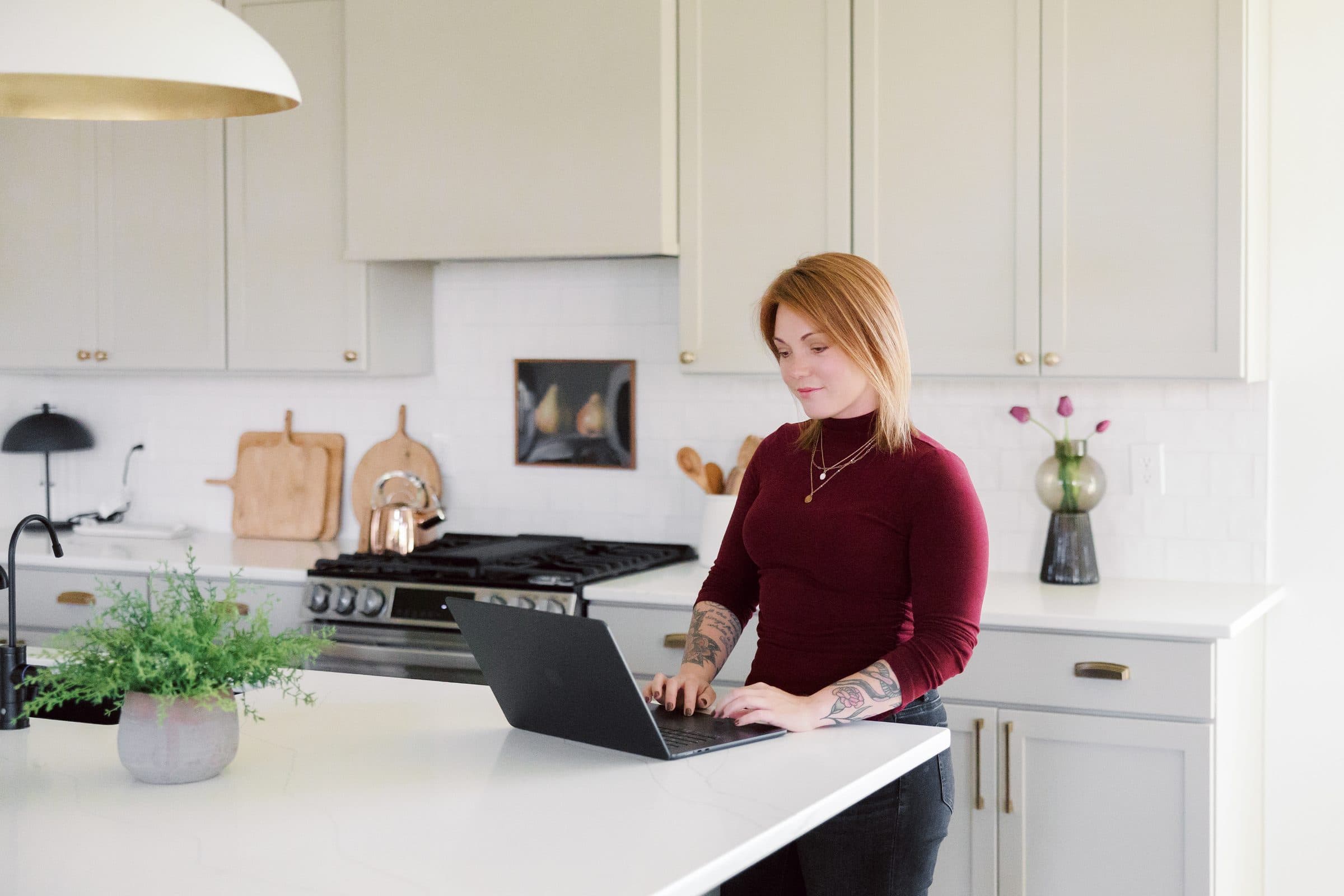 Jenna Gray, Dayton realtor, working at a laptop on a kitchen island