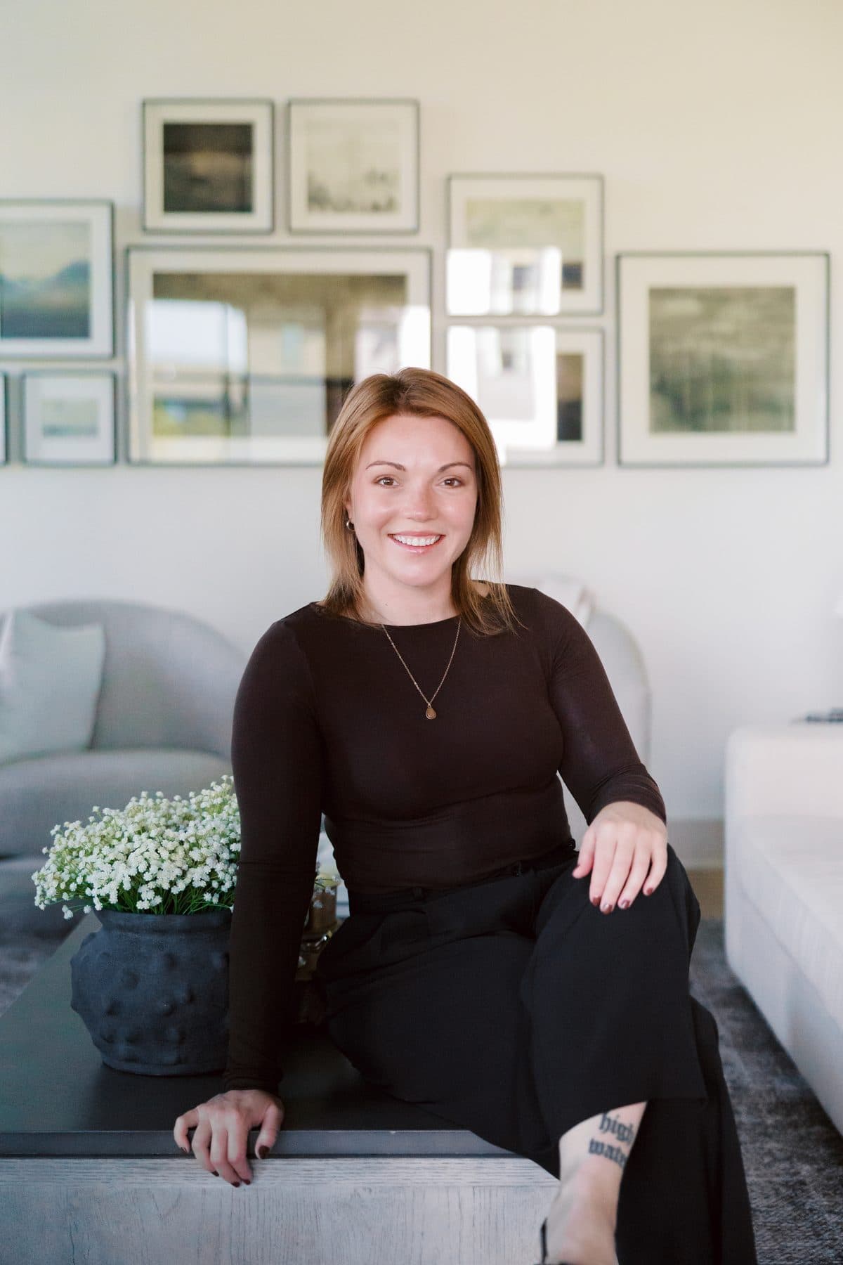 Jenna Gray, Dayton realtor, seated on a coffee table in a living room