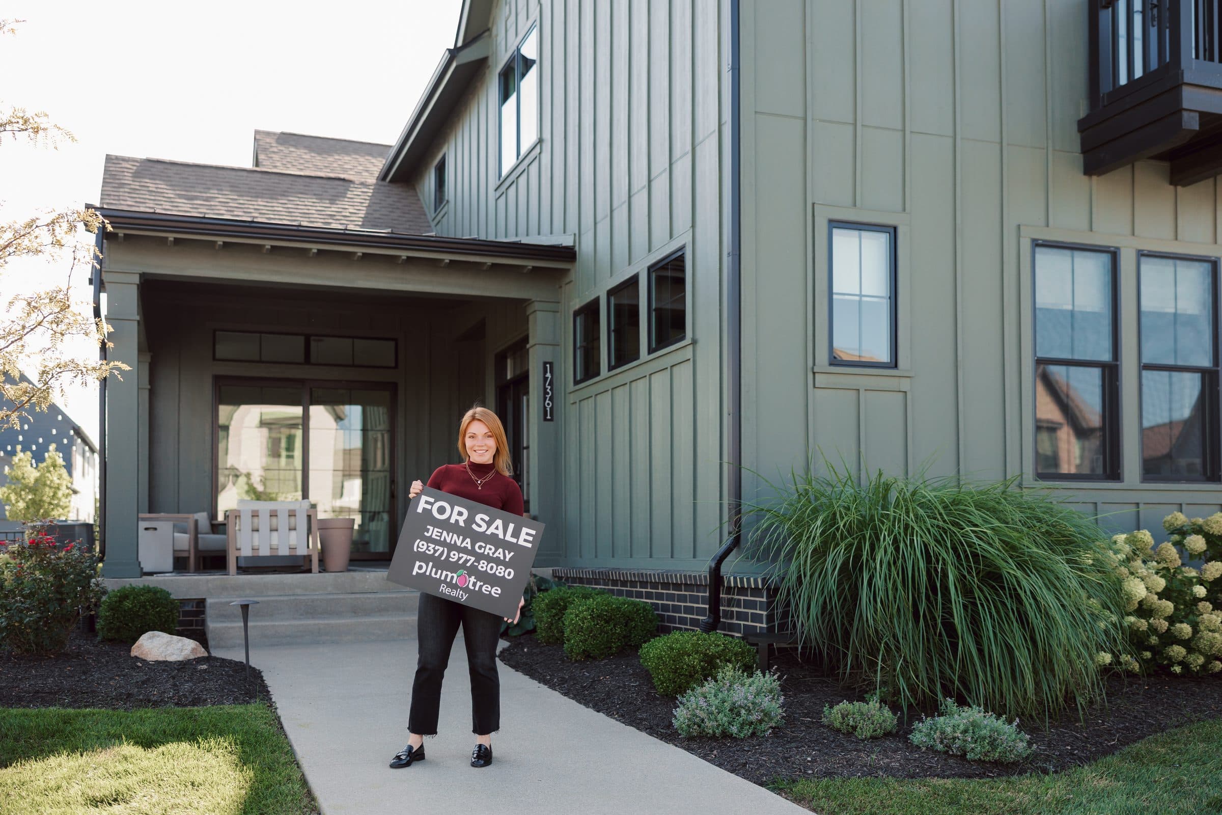 Jenna Gray, Dayton realtor, with a Plum Tree Realty for sale sign in front of a listing