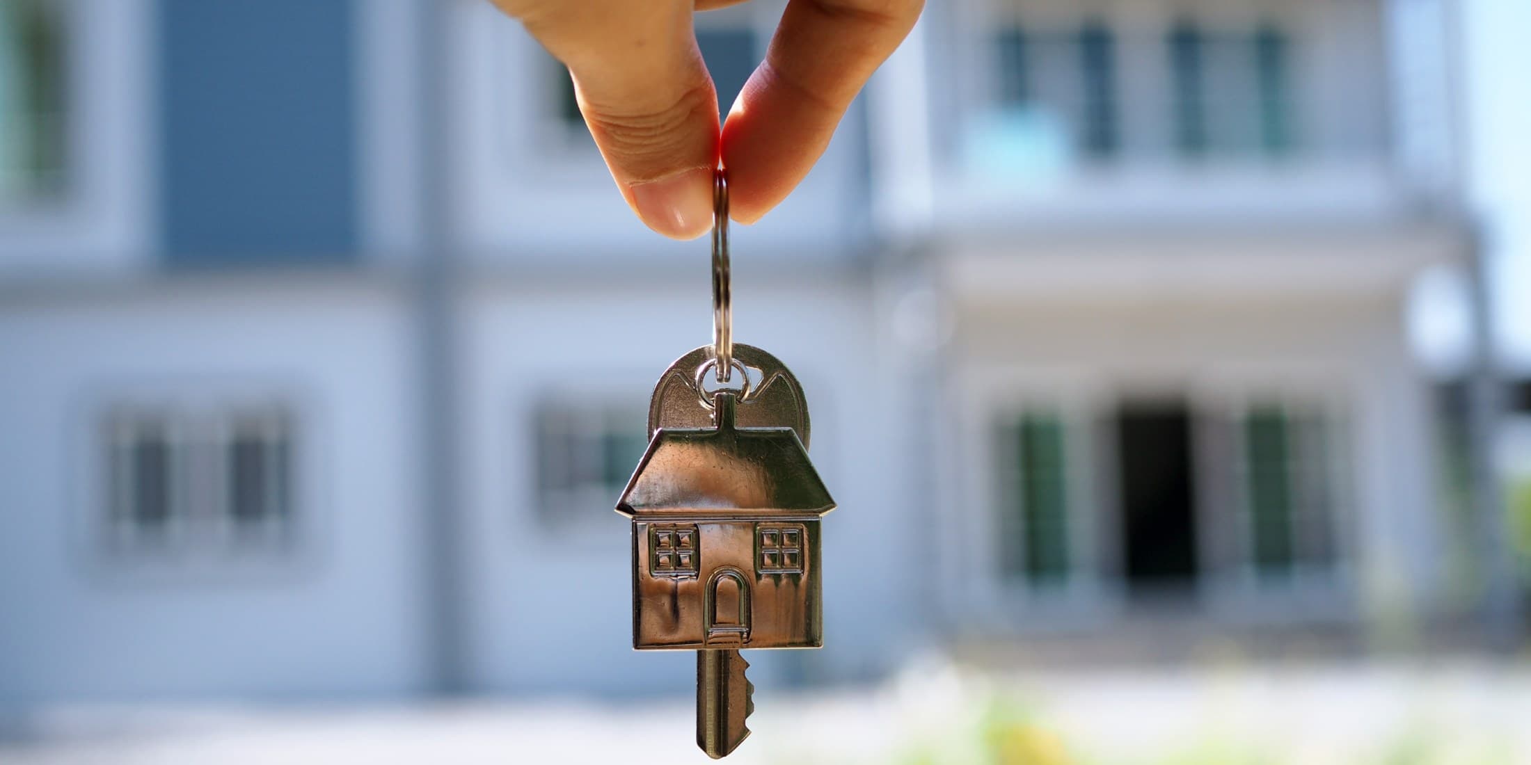 House-shaped keys handed over in front of a home