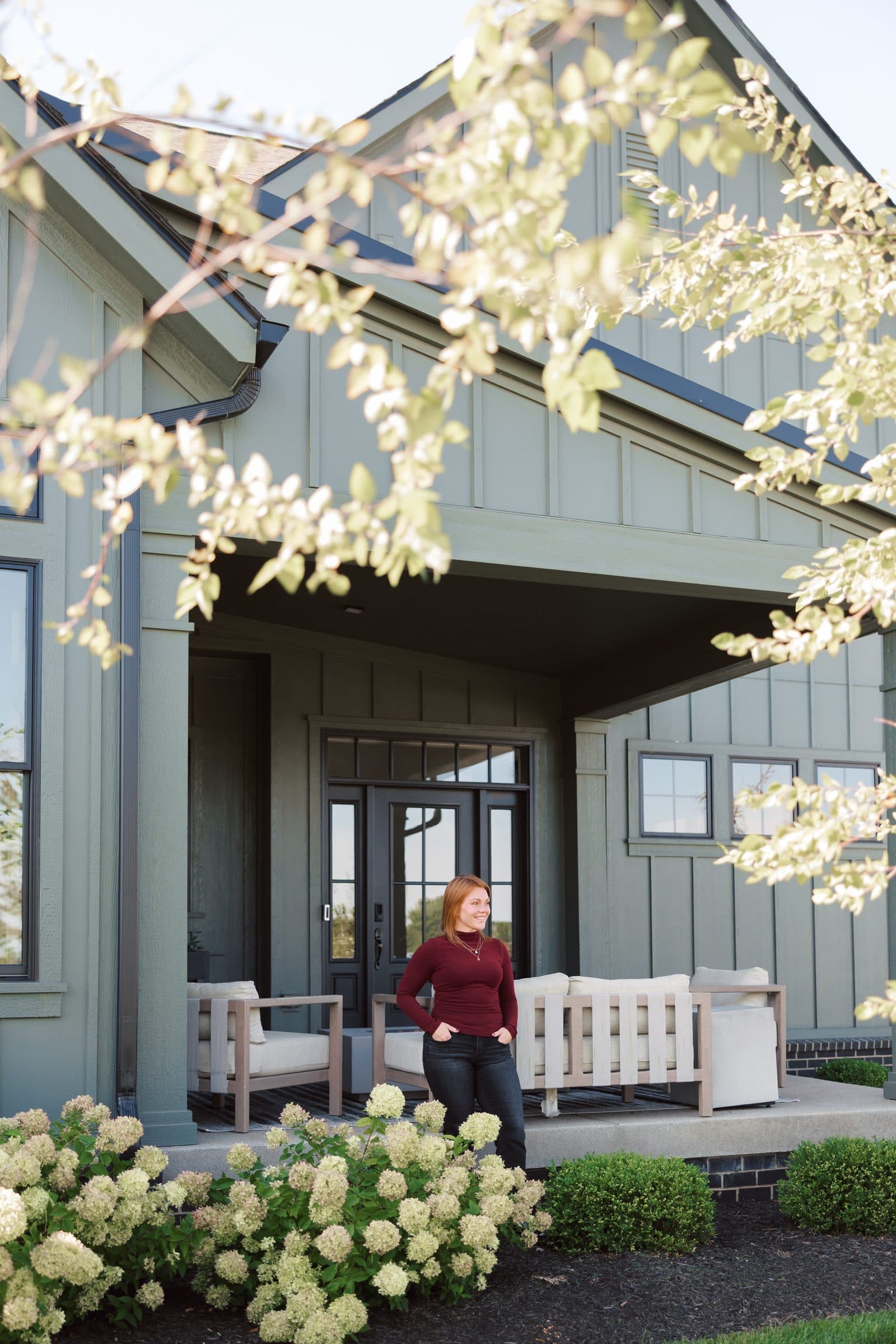A board and batten house with hydrangeas in the Dayton area, Jenna Gray on the porch